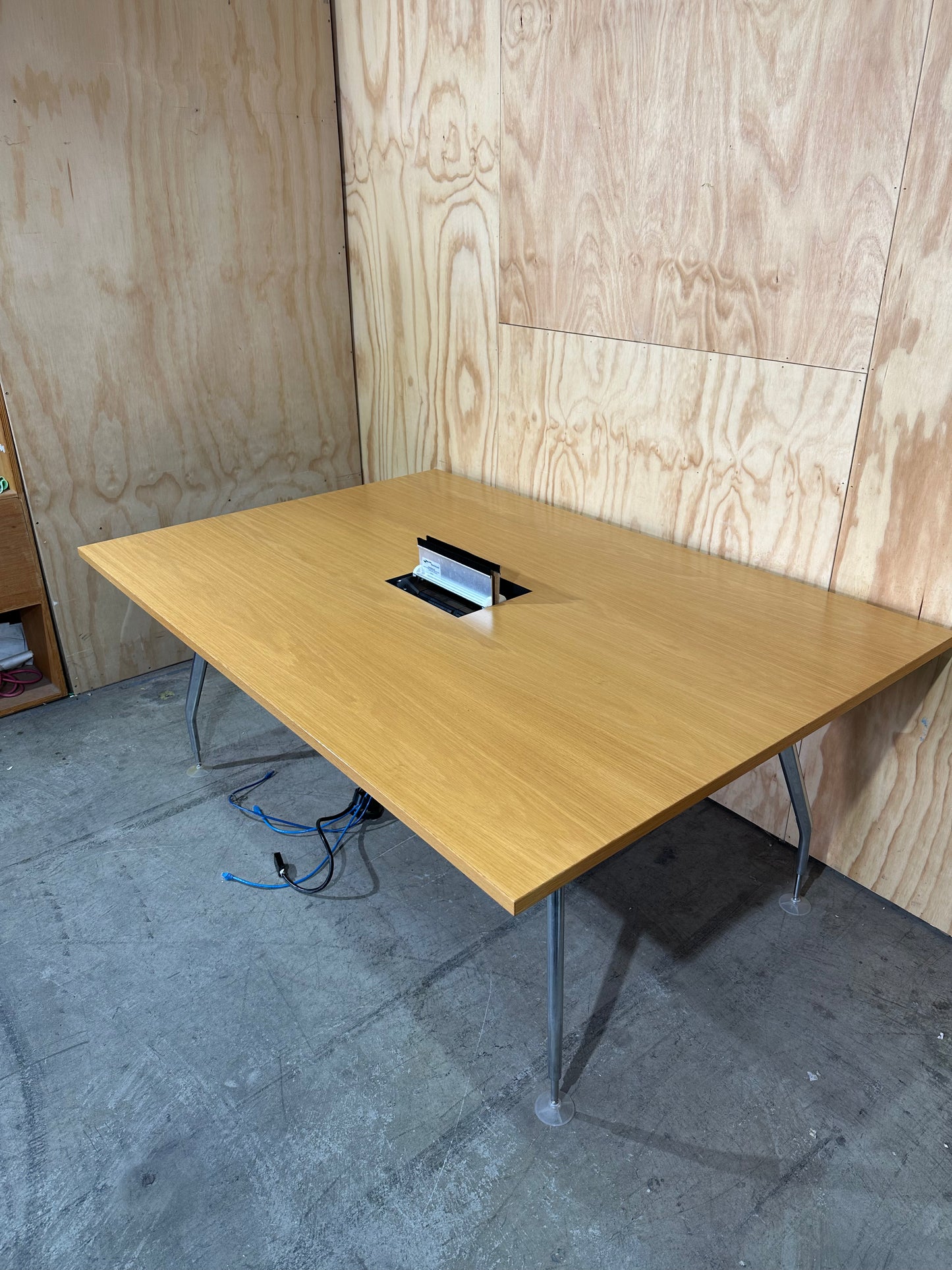 Wide wooden meeting table with cable management on chrome legs